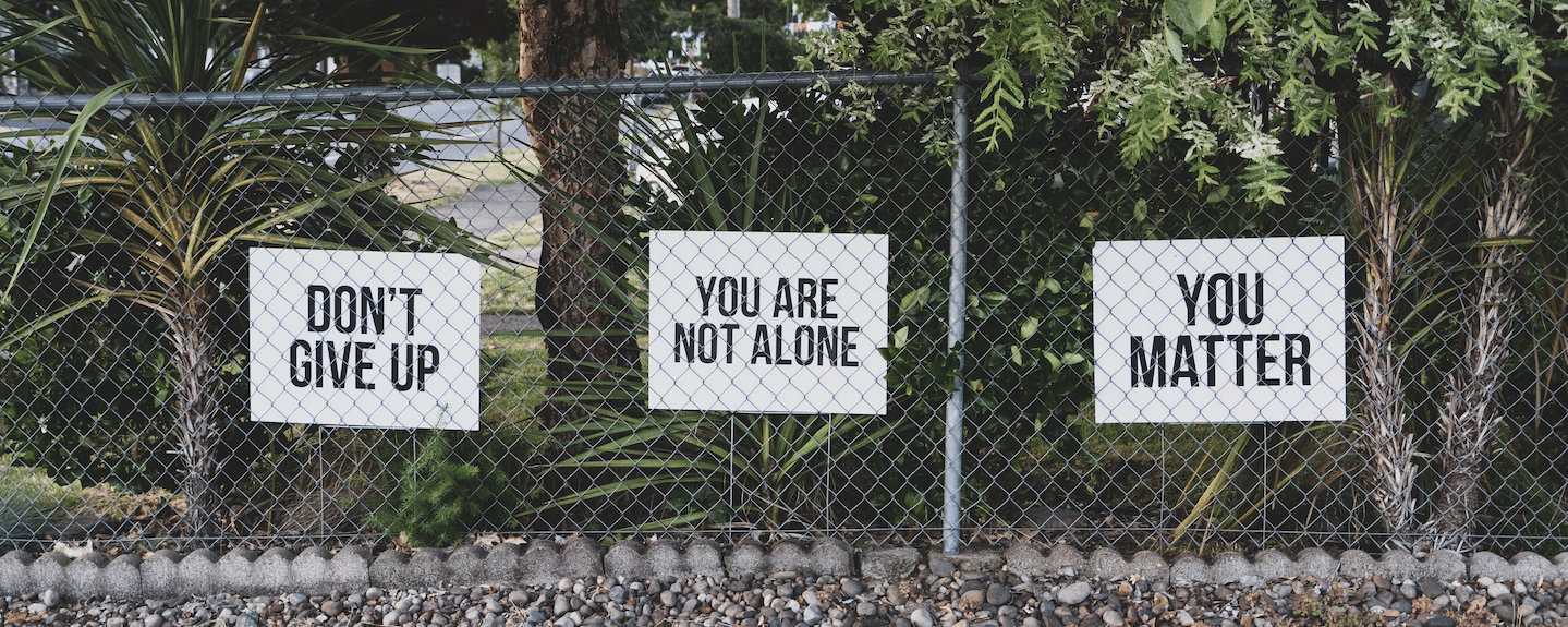 Caring signs on a fencepost, saying "don't give up, you matter, you are not alone